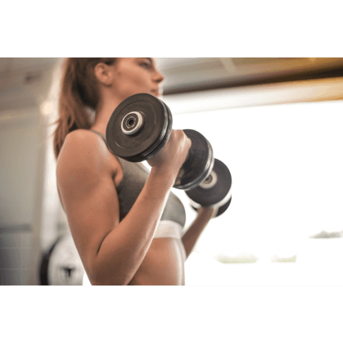 Woman in workout attire lifting dumbbells in a gym setting, focusing on her exercise routine.